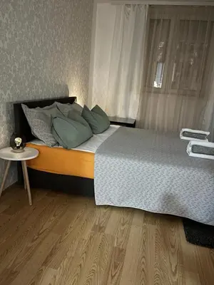 a bed with green pillows and a table in a room at Lana Apartman in Niš