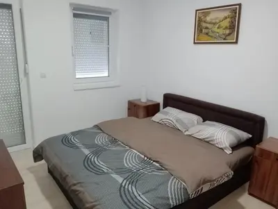 a bed in a white room with two pillows at Apartman Petrovic 4 in Soko Banja