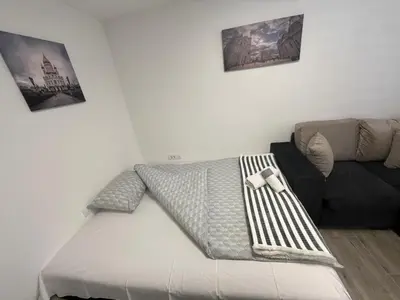 a bed in a living room with a couch at Apartman city in Niš