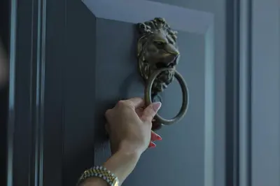 a person is unlocking a door with a lion handle at Vila Safra in Vrnjačka Banja