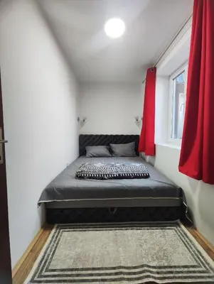 a bed in a small room with a red curtain at Milijic Lux 2 in Soko Banja