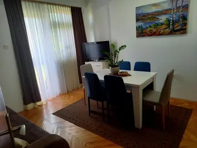 a dining room table with chairs and a tv at Apartman KEJ 64m2 in Surdulica