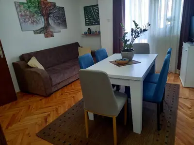 a living room with a white table and blue chairs at Apartman KEJ 64m2 in Surdulica
