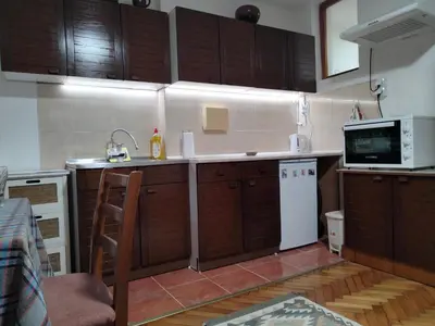 a kitchen with wooden cabinets and a white refrigerator at Apartment studio Ignjatovic in Niš