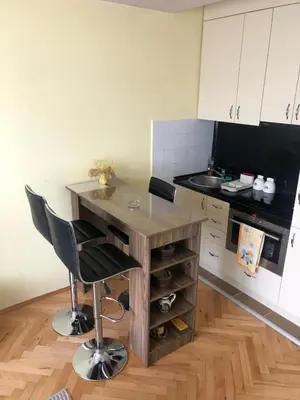 a kitchen with a wooden table and black chairs at ANNI apartman in Paraćin