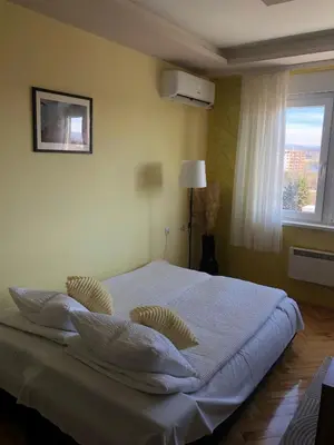 a bedroom with a bed with white sheets and a window at ANNI apartman in Paraćin