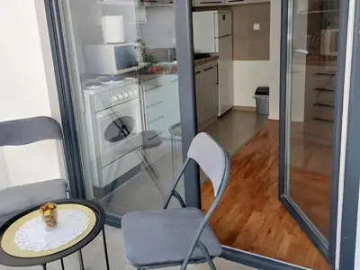 a room with a table and chairs and a kitchen at Slatki Snovi - Novi apartman u centru Vranja in Vranje