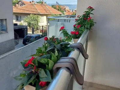 a balcony with red flowers on the ledge of a building at Slatki Snovi - Novi apartman u centru Vranja in Vranje