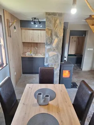 a wooden table and chairs in a kitchen with a fireplace at Planinska kuća Radulović in Goč