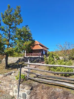 a house on top of a hill with a fence at Planinska kuća Radulović in Goč