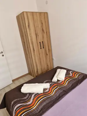 a bed with two towels and a wooden door at Apartman Curcic 1 in Soko Banja