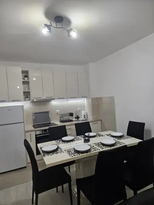 a kitchen with a table and chairs and a kitchen with white cabinets at Apartman Ćurčić in Soko Banja