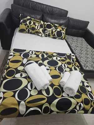 a bed with a black and yellow blanket and pillows at Apartman Ćurčić in Soko Banja