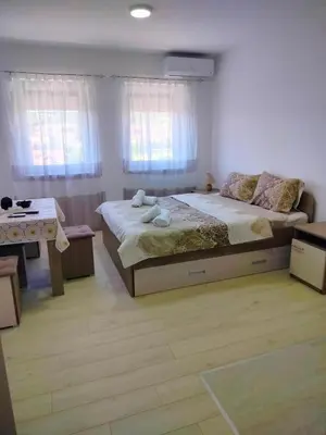 a bedroom with a bed and a desk and windows at Studio Marija 21 in Soko Banja