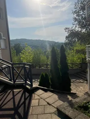 a bench sitting on a patio with a view of trees at Apartman Anja in Vrnjačka Banja