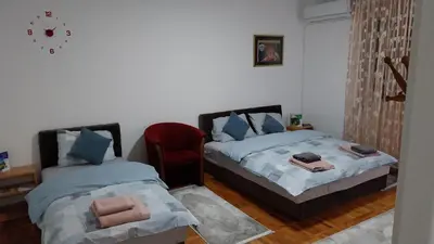a bedroom with two beds and a red chair at Apartman EmEm in Kuršumlija
