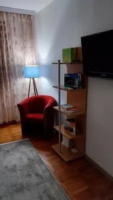 a living room with a red chair and a television at Apartman EmEm in Kuršumlija