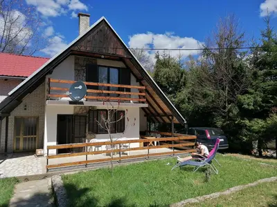 a man sitting in a chair in front of a house at Vlasinsko jezero vila BiLiV in Surdulica