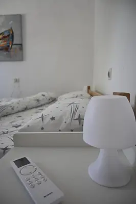 a white bedroom with a bed and a remote control at Mokino bunarče in Knjazevac.