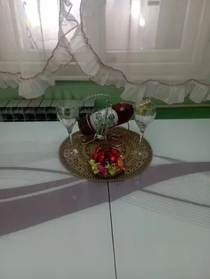 a plate with a bottle and two glasses on a table at Apartman Icić in Pirot