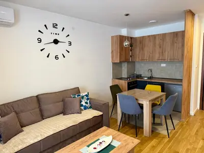 a living room with a couch and a clock on the wall at Luxe Apartman Sokobanja in Soko Banja