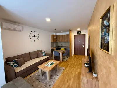 a living room with a couch and a clock on the wall at Luxe Apartman Sokobanja in Soko Banja