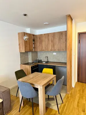 a kitchen and dining room with a wooden table and chairs at Luxe Apartman Sokobanja in Soko Banja
