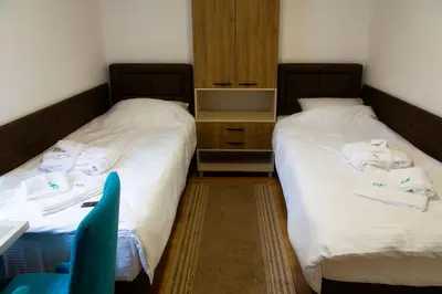 two beds in a room with a chair and a desk at Sobe Lucky in Ribarska Banja