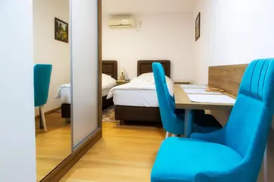 a room with a table and blue chairs and a bed at Sobe Lucky in Ribarska Banja