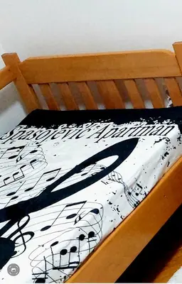 a bed with a black and white comforter on it at Spasojević Apartman in Kuršumlija