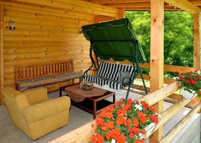 a porch of a log cabin with a couch and a table at Deda Misina Koliba in Ćuštica