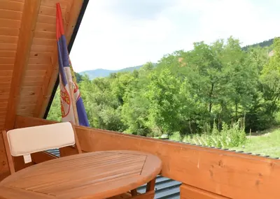a table and a chair on a balcony with a view at Deda Misina Koliba in Ćuštica