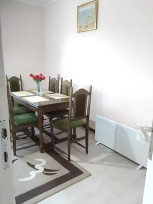 a dining room table and chairs with a vase of flowers at Lina apartment in Lebane