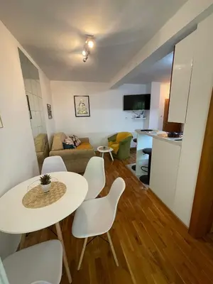 a living room with a table and chairs and a kitchen at Apartman Anika in Soko Banja