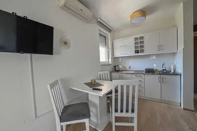 a kitchen with a table and two chairs and a kitchen with white cabinets at Zlatnik Vrnjačka Banja in Vrnjačka Banja