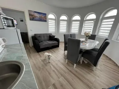a living room with a table and a white dog at Apartman LOKI in Soko Banja