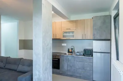 a kitchen with stainless steel appliances and a couch at Apartmani Putnik in Vrnjačka Banja