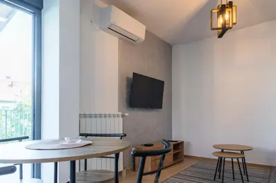 a living room with a table and chairs and a tv at Apartmani Putnik in Vrnjačka Banja