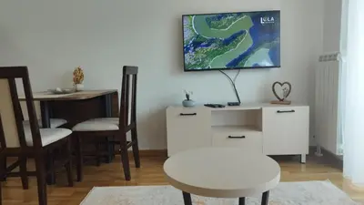 a living room with a table and a tv on the wall at Apartman NEMANJA in Vrnjačka Banja