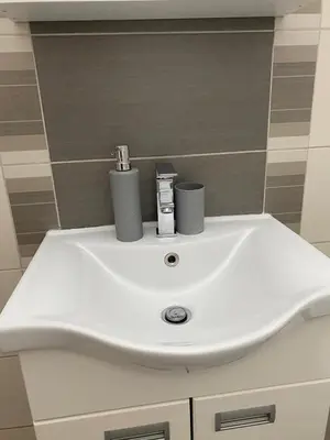 a white bathroom sink with two cups on it at Niki Apartman in Kruševac