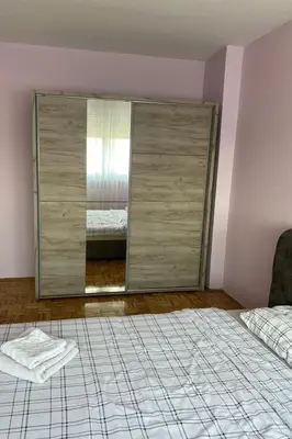 a bedroom with a large glass closet with a bed at Niki Apartman in Kruševac