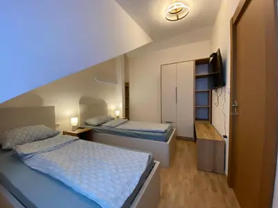 a bedroom with two beds and a television in it at Kraljica apartman in Vrnjačka Banja