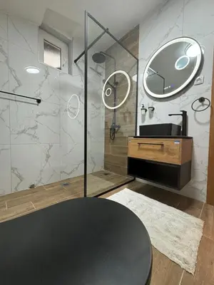 a bathroom with a sink and a shower with a mirror at Kraljica apartman in Vrnjačka Banja