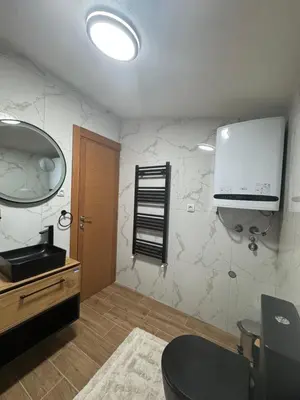 a bathroom with a toilet and a tv on the wall at Kraljica apartman in Vrnjačka Banja