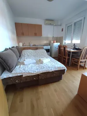 a bedroom with a bed and a kitchen with a table at Sunrise apartment Sokobanja in Soko Banja