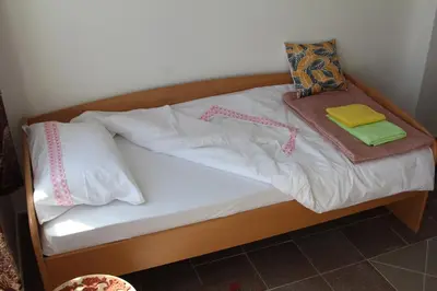 a bed with white sheets and pillows on it at Apartmani Borovi in Pirot