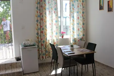 a dining room with a table and chairs and a window at Apartmani Borovi in Pirot