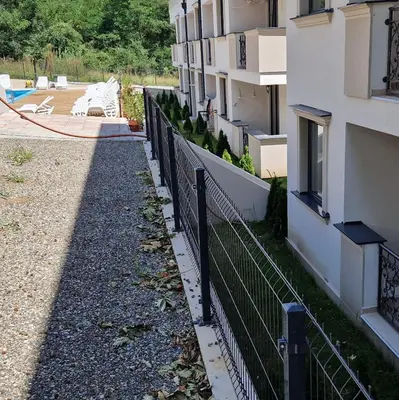 a fence next to a building with a pool at MB LUX Residence in Vrnjačka Banja