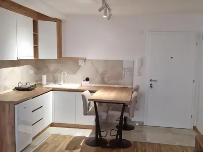 a kitchen with a wooden table and white cabinets at MB LUX Residence in Vrnjačka Banja