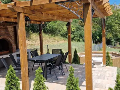 a patio with a table and chairs under a wooden pergola at MB LUX Residence in Vrnjačka Banja
